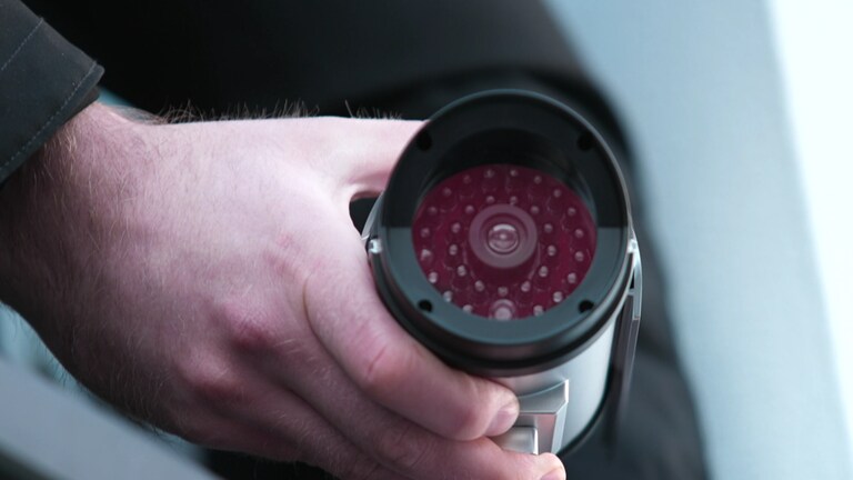 Eine Kamera-Attrappe ist eine kostengünstige und einfache Alternative zur Installation einer echten Überwachungskamera. Ein Mann installiert draußen eine Kamera-Attrappe.